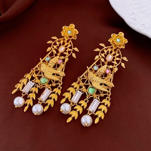 Dettaglio di orecchini vintage in oro con strass colorati e perle bianche naturali