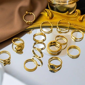 Collection of gold titanium rings with bow, smile, and roman numeral designs on satin