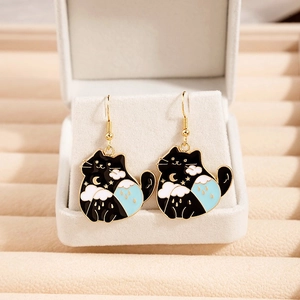 Cute black cat enamel earrings with moon and star details on a beige display stand