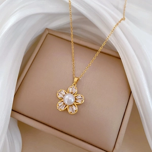 Detailed macro of a gold five-petal flower pendant with white pearl and baguette zircons