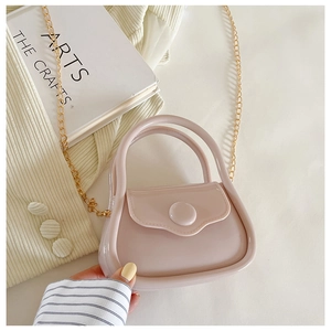 Detail of pink mini jelly bag with gold chain strap on a soft knit sweater background