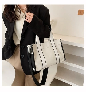 Detail of canvas tote bag with black contrast trim and wide shoulder strap