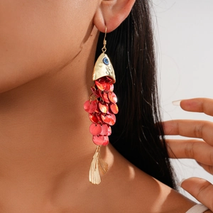 Detail of articulated red sequin fish earrings with golden metal fins on a model