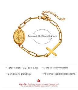 Detail of gold paperclip chain bracelet with Virgin Mary medal and cross charm