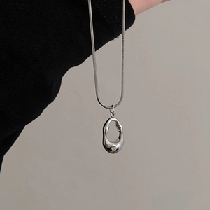 Close-up of minimalist silver stainless steel necklace with liquid metal style pendant