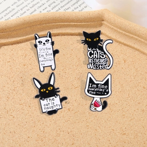 Set of four vintage cartoon cat enamel pins in black and white finish on a tray