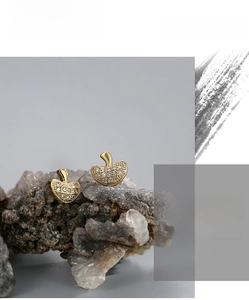 Macro shot of gold-plated mushroom-shaped stud earrings with white zircon on stone