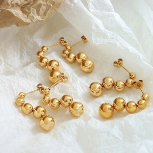 Elegant gold bead stud earrings with graduated metallic spheres on textured paper