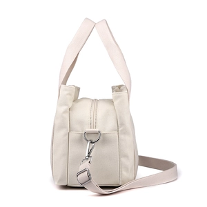 Women's cream canvas handbag with top handles and adjustable shoulder strap, side view