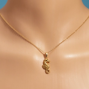 Nahaufnahme einer goldenen Seepferdchen-Halskette an einem Modell für einen maritimen Look