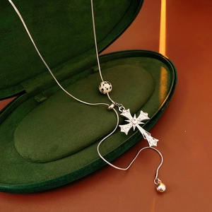 Detail of silver snake chain with tiger eye cross pendant in green velvet box