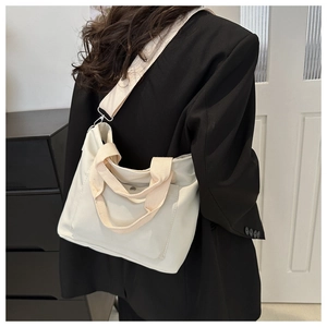 Detalle del bolso tote de lona blanco roto con bolsillo y correa ajustable