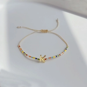 Detailaufnahme des bunten Perlenarmbands mit goldenem Buchstaben-Anhänger K
