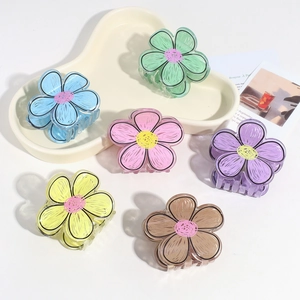 Close-up of translucent flower hair claws in six colors on a white ceramic tray