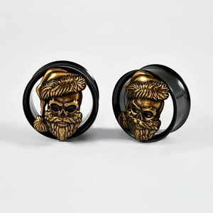 Close-up of golden Santa skull ear gauges with black rings on white background