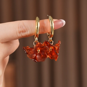Macro detail of vintage gold hoop earrings with translucent amber resin flower petals