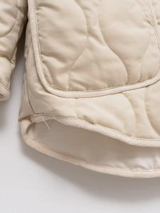 Macro shot of quilted air cotton jacket featuring beige fabric and woven edge trim