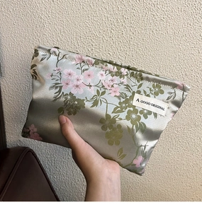 Detail of silver silk makeup bag featuring exquisite pink floral embroidery and label