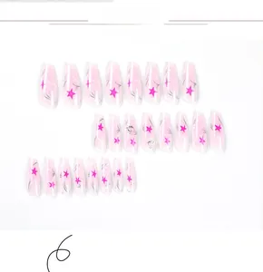 Dettaglio di unghie finte lunghe a bara con sfumatura rosa e motivi a stella