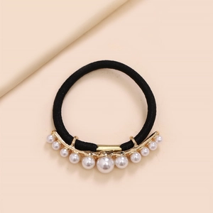 Macro view of black elastic hair tie with curved gold alloy bar and varied size white pearls