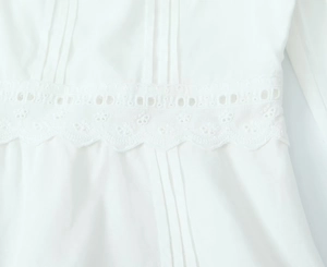 Gros plan sur un chemisier blanc avec broderie de dentelle complexe et détails plissés