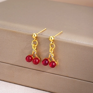 Sparkling cherry pendant earrings with red crystal and gold-tone finish on a jewelry box