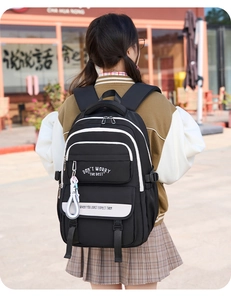 Detailed back view of a black nylon backpack with white stripes and contrast text design