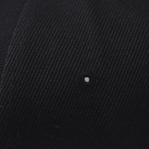 Vue macro de la texture du tissu sergé noir et de l'œillet d'aération brodé sur la casquette