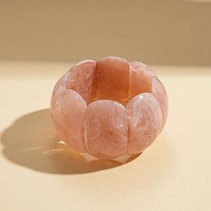 Vue détaillée d'un bracelet en acrylique marbré rose au design géométrique de pétales
