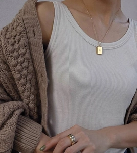 Close-up of a vintage gold starburst pendant necklace worn with a minimalist knit cardigan