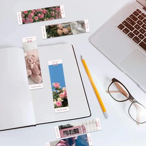 Flat lay of pink aesthetic bookmarks with rose and teddy bear prints on a desk
