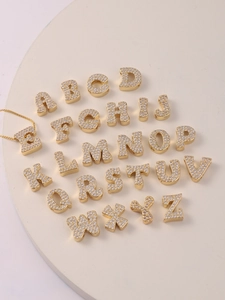 Detaillierte Makroaufnahme von 26 Buchstaben-Anhängern mit funkelnden Zirkonia auf Goldfinish