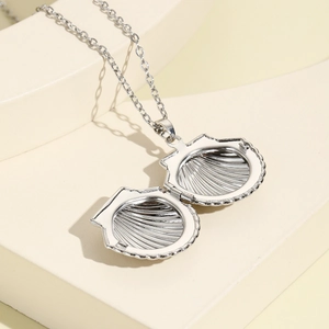 Macro view of shell locket necklace with ribbed texture on geometric display stand
