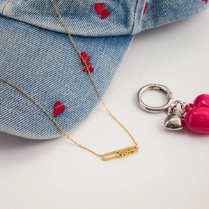 Dettaglio del ciondolo a spilla in oro 18K con scritta LOVE e pietre luccicanti