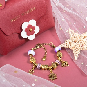 Detailed view of DIY pink charm bracelet with gold crown pendant and Best Wishes gift bag