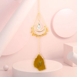 Detail of golden moon frame with natural yellow agate slice and teardrop crystal prism