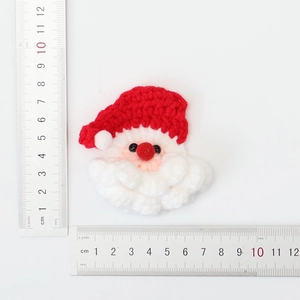 Père Noël tricoté à la main montrant des dimensions de 6 cm avec une règle en acier