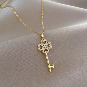 Luxury gold four-leaf clover key necklace with sparkling diamonds on silk background