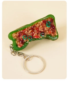 Detailed macro view of a realistic PVC stuffed green chili pepper keychain with sauce