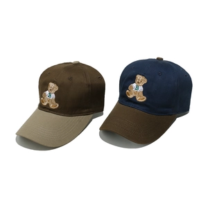 Close-up of color-block baseball caps with detailed bear embroidery on cotton twill fabric