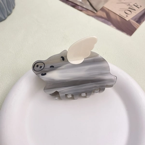 Close-up of pig-shaped acetate hair claw with marble texture and white wings