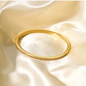 Dettaglio del bracciale placcato oro 18k con zirconi bianchi su elegante tessuto satin