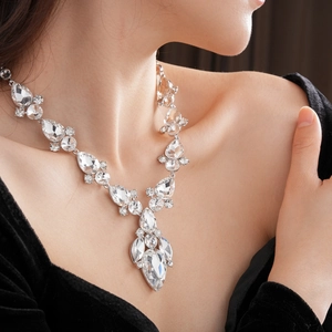 Primo piano di una collana di lusso con cristalli a goccia e foglie indossata dal modello