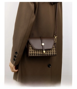 Detail of vintage houndstooth canvas and brown leather crossbody bag on a wool coat
