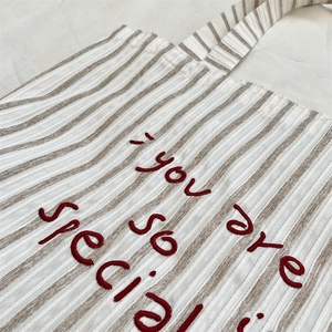 Detail of red embroidery on striped canvas bag with you are so special text