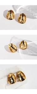 Detailed view of large gold textured oval earrings showing handmade hammered metal finish
