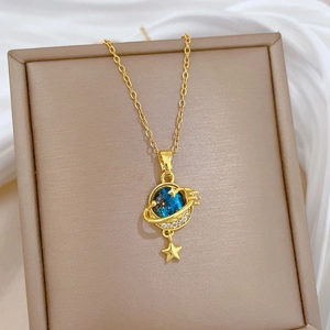 Elegant gold necklace with blue galaxy planet pendant and star charm on jewelry box