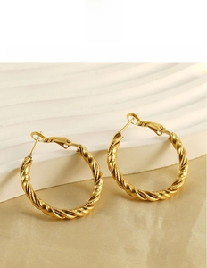 Detail of gold twisted hoop earrings in titanium steel with a secure snap closure