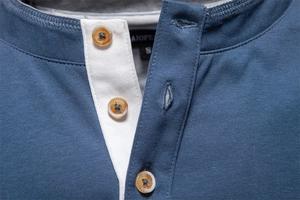 Close-up of contrast white Henley neck with resin buttons on blue cotton knit shirt