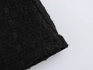 Macro della trama del tessuto in tweed nero e dei motivi intrecciati sull'abito